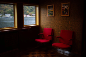 Bancos vermelhos em sala com vista para o mar e quadros na parede